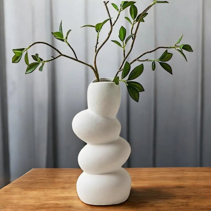 Aesthetic white ceramic wave flower vase featuring a sculptural design with green branches.